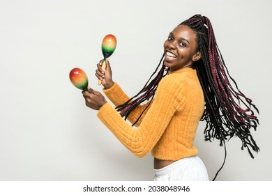 Cheerful black woman enjoying maracas isolated on a gray background - Powered by Shutterstock