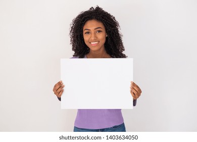 Cheerful black woman holding white banner and copy space - Powered by Shutterstock