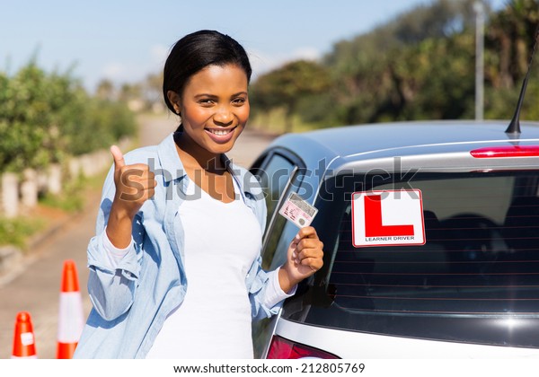 cheerful black woman showing a driving license she\
just got
