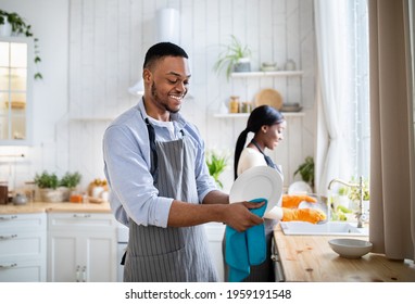 Cheerful black woman washing dishes while her husband wiping them at kitchen, copy space. Young African American family performing household duties together, doing domestic chores - Powered by Shutterstock