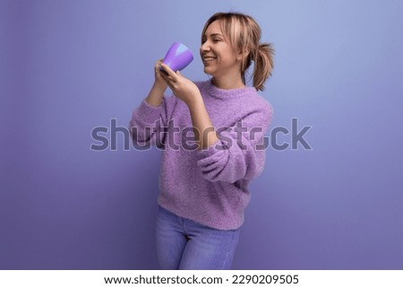 cheerful blond young millennial woman in a casual look with a cup of coffee on a bright background with copy space