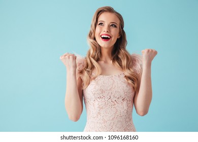 Cheerful blonde woman in dress rejoices and looking up over turquoise background - Shutterstock ID 1096168160