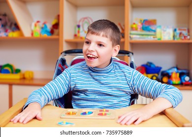 cheerful boy with disability at rehabilitation center for kids with special needs, solving logical puzzle - Shutterstock ID 735975889