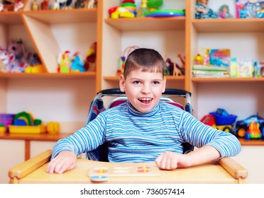 cheerful boy with disability at rehabilitation center for kids with special needs, solving logical puzzle - Shutterstock ID 736057414