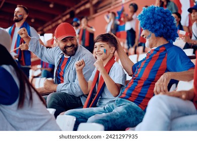 Cheerful boy with his father and grandfather watching sports match at the stadium. - Powered by Shutterstock