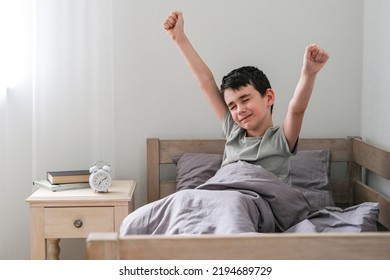 Cheerful boy stretches after waking up in bed. Morning of the schoolboy - Powered by Shutterstock