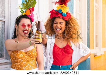 Cheerful brazilian women having fun at street Carnival. Carnaval in Brazil, girls celebrating and toasting party together.