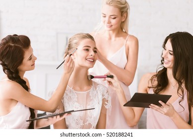 Cheerful bridesmaids helping the bride to get ready - Powered by Shutterstock