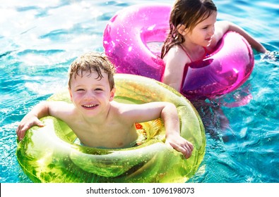 Cheerful brother and sister swimming in the pool