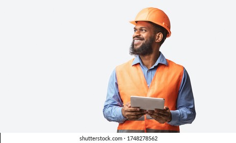 Cheerful Builder Holding Digital Tablet Smiling Looking Aside Posing On White Studio Background. Free Space, Panorama