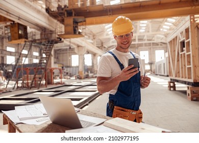 Cheerful builder using smartphone at construction site - Powered by Shutterstock