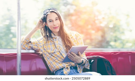 Cheerful business female traveling, sitting in MRT train. Enjoying travel. Caucasian traveler woman traveling by Mass Rapid Transit(MRT) train using tablet, smartphone. Transportation, travel concept. - Powered by Shutterstock