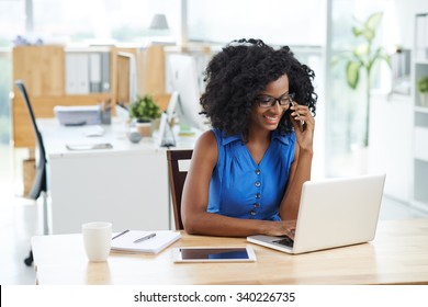 Cheerful Business Lady Talking On The Phone When Using Laptop