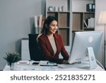 Cheerful business lady working on laptop in office, Asian happy beautiful businesswoman in formal suit work in workplace. Attractive female employee office worker smile.