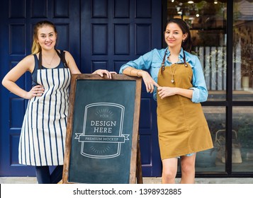 Cheerful business owners standing with blackboard mockup