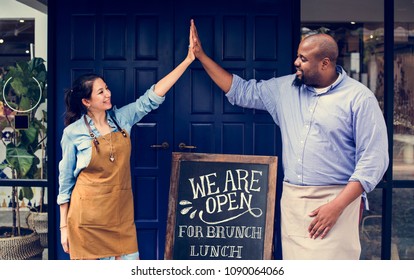 Cheerful business owners standing with open blackboard