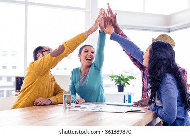 Cheerful business team doing high five while sitting in creative office