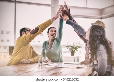 Cheerful Business Team Doing High Five While Sitting In Creative Office