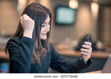 A Cheerful Business Woman Looks At The Phone With 