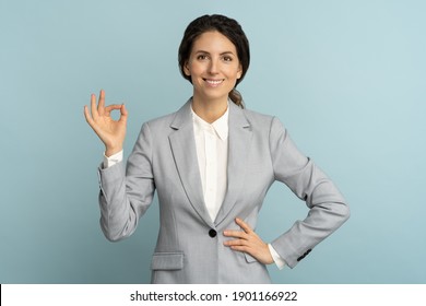 Cheerful Business Woman Wear Blazer In Good Mood Smiling Broadly, Showing Ok Sign Over Studio Blue Color Background. Positive Office Employee Female Advertises A Product. Customer, Sale, Discount. 