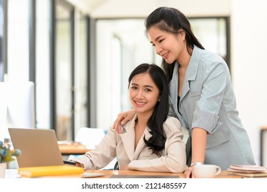 Cheerful Business Women Coworker In Modern Office, Working On Project Together. Kind Female Boss Training Her Assistant In The Office