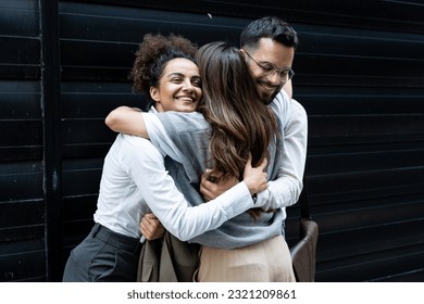 Cheerful businessman and businesswomen hugging each other in front of office building. Colleagues hug colleague who change her job and work, going to another company. - Shutterstock ID 2321209861