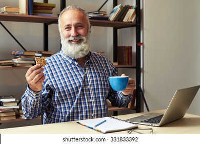 cheerful businessman having coffee break at his working place
