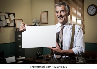 Cheerful Businessman Showing A Blank Sign And Smiling, 1950s Office On Background.