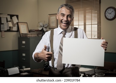 Cheerful Businessman Showing A Blank Sign And Smiling, 1950s Office On Background.