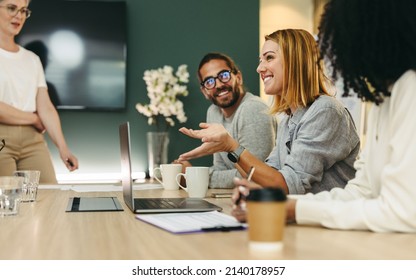 Cheerful businesswoman having a discussion with her colleagues in a boardroom. Group of happy businesspeople sharing ideas during a meeting in a modern workplace. - Powered by Shutterstock