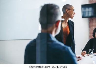 Cheerful businesswoman leading a meeting with her colleagues in an office. Group of creative businesspeople attending their morning briefing in a modern workplace. Businesspeople working together.