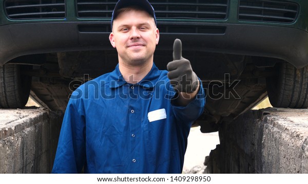 A cheerful car repairman on the street repairs\
the engine and lower part of the car, shows different emotions,\
dances with a big wrench.  
