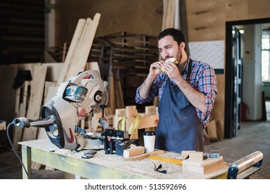 Cheerful carpentry worker having lunch eating sandwich in a workshop - Powered by Shutterstock