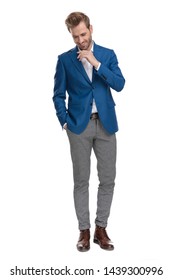 Cheerful casual men laughing and holding his hand in his pocket while looking down and wearing a suit, standing on white studio background