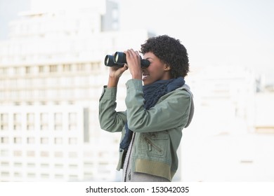 Cheerful casual model looking through binoculars outdoors on a sunny day