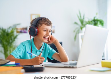 cheerful Caucasian boy with headphones uses laptop to make video call with his teacher. child is happy to learn remotely. He happy to receive knowledge. E-Education Distance Learning, Home Schooling. - Powered by Shutterstock