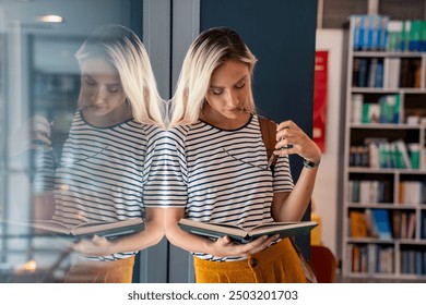 A cheerful Caucasian female student in a striped top exudes positivity as she peruses a book, leaning against a sunlit library window, reflecting her dedication to learning. - Powered by Shutterstock