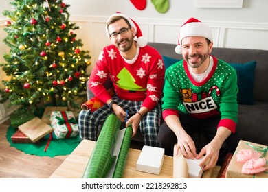 Cheerful Caucasian Gay Couple Wearing Christmas Pajamas Wrapping Family And Friends Presents For The Holidays