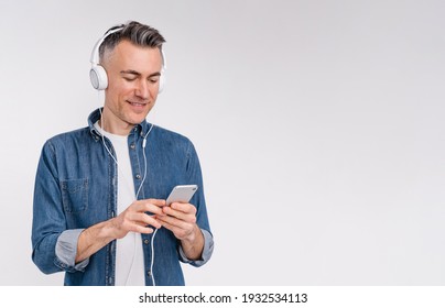 Cheerful caucasian man listening to the music in headphones on the phone isolated over white background - Powered by Shutterstock