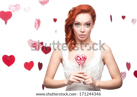 cheerful caucasian red-haired surprised young woman holding lollipop. isolated on white