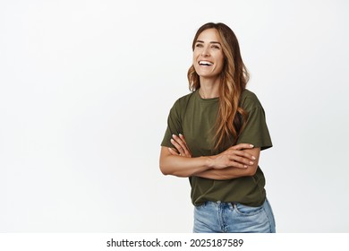 Cheerful caucasian woman cross arms on chest, laughing and smiling white teeth, looking aside left at promo text, posing with cheerful face expression, studio background