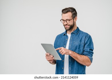 Cheerful caucasian young man student freelancer using digital tablet for social media, e-banking, mobile application, e-learning isolated in white background