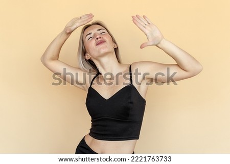 A cheerful caucasian young woman grimacing, fooling and dance around on beige background. Humor concept