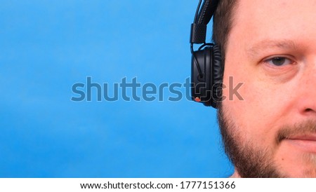 Cheerful charismatic fat man in headphones isolated and pink t-shirt on a blue background. listen to music, sing and dance.