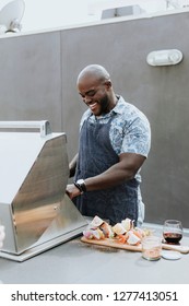Cheerful chef grilling barbeque skewers at a rooftop party