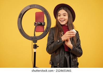 cheerful child do makeup. vlogger with powder brush. making video blog on phone.