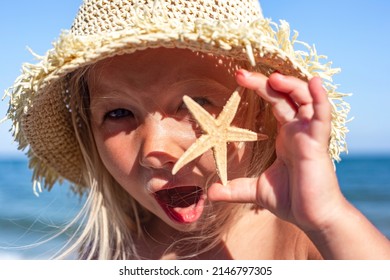 Cheerful Child Girl In Panama Holding A Starfish On The Beach 