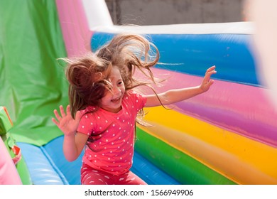 A cheerful child plays in an inflatable castle - Shutterstock ID 1566949906