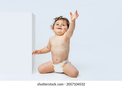 Cheerful Child. Portrait Of Little Sweet Toddler Boy, Baby In Diaper Calmly Sitting, Smiling Isolated Over White Studio Background. Concept Of Childhood, Motherhood, Life, Birth. Copy Space For Ad
