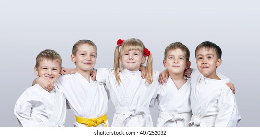 Cheerful children in karategi on a gray background